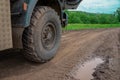 View from a wheel of the off-road truck riding in a dirt road on cloudy sky background. Scene. Close up for red cab of a lorry Royalty Free Stock Photo