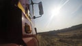 View from a wheel of the off-road truck riding in a dirt road on cloudy sky background. Scene. Close up for red cab of a Royalty Free Stock Photo