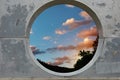 View of white clouds in sunset sky through hole in concrete wall Royalty Free Stock Photo