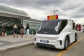 View of a white ETIOCA full electric minivan taxi parked before a station buildingtranslation: taxi