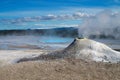 View on white fumarole mini volcano crater cone geyser emitting sulphuric gas, steaming hot blue natural pool on geothermal field