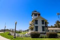 A view of a white and green lighthouse in the park with a white picket fence surrounded by lush green grass and trees Royalty Free Stock Photo