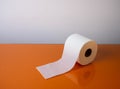 View of a white toilet paper roll over an orange background