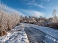 View of white winter landscape with trees covered with snow, frozen puddle and country road after a heavy snowfall Royalty Free Stock Photo