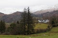 View of whitewashed farmhouse in the Lake District looking toward snowcapped peaks