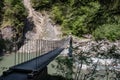 View of a wild river in a gorge with a modern hanging bridge