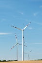 View of a wind power plant on a background of blue sky and fields with grain crops. The concept of environmental electricity produ Royalty Free Stock Photo