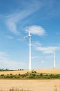 View of a wind power plant on a background of blue sky and fields with grain crops. The concept of environmental electricity produ Royalty Free Stock Photo