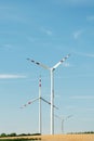 View of a wind power plant on a background of blue sky and fields with grain crops. The concept of environmental electricity produ Royalty Free Stock Photo