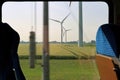 View of wind turbine from empty comfortable blue seat with sunlight through window in a modern German train Royalty Free Stock Photo