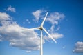 View of a wind turbine on top of mountains, blue sky as background