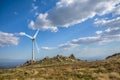 View of a wind turbine on top of mountains, blue sky as background