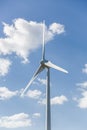 View of a wind turbine on top of mountains, cloudy sky as background