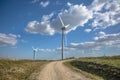 View of a wind turbines on top of mountains, cloudy sky as background