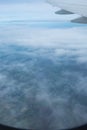 A view through the window of an airplane that sees the city, the fields, the sea and the clouds