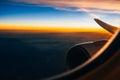 View through the window of the airplane on the wing and turbine at sunrise against the cloudy sky Royalty Free Stock Photo