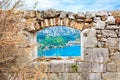 View through a window in ancient stone wall of a medieval fortress to the sea landscape and coast town. Royalty Free Stock Photo