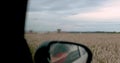 View from the window of a car moving along a field on which work is underway to collect waste.