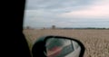 View from the window of a car moving along a field on which work is underway to collect waste.