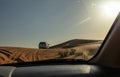 The view from the window of the jeep on the white closed jeep Toyota extremely drives through the sandy desert near Dubai city,