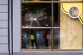 View through the window of a man in a cafe writing a message on a smartphone and drinking coffee