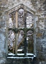 View through a window of a medieval ruined church in heptonstall yorkshire with snow covered trees behind the stone frame