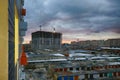 View from the window of a new house on the area under construction. Old and new city against the cloudy sky. Sunset in the Royalty Free Stock Photo