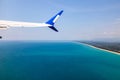 view from the window of the plane on the wing against the background of the blue sea, sky and coast of the island. travel and Royalty Free Stock Photo