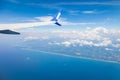 view from the window of the plane on the wing against the background of the blue sea, sky and coast of the island. travel and Royalty Free Stock Photo