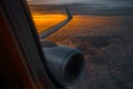 View from the window to airplane wing and engine at sunrise, flying above the clouds Royalty Free Stock Photo