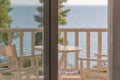 view from window to loggia with table and chairs and to sea