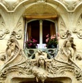 View of a window and a window box with geraniums in a building with sculptures in Paris, France