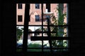 View through the windows of an unfinished house to a building with broken windows