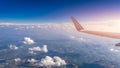 View of the wing of an airplane flying above the clouds at high altitude under a blue sky from the passenger window. In flight Royalty Free Stock Photo