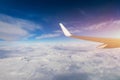 View of the wing of an airplane flying above the clouds at high altitude under a blue sky from the passenger window. In flight Royalty Free Stock Photo