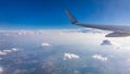 View of the wing of an airplane flying above the clouds at high altitude under a blue sky from the passenger window. In flight Royalty Free Stock Photo