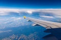 View of the wing of an airplane flying above the clouds at high altitude under a blue sky from the passenger window. In flight Royalty Free Stock Photo