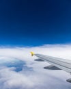 View of the wing of an airplane flying above the clouds at high altitude under a blue sky from the passenger window. In flight Royalty Free Stock Photo