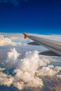 View of the wing of an airplane flying above the clouds at high altitude under a blue sky from the passenger window. In flight Royalty Free Stock Photo