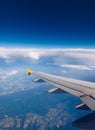 View of the wing of an airplane flying above the clouds at high altitude under a blue sky from the passenger window. In flight Royalty Free Stock Photo