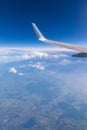 View of the wing of an airplane flying above the clouds at high altitude under a blue sky from the passenger window. In flight Royalty Free Stock Photo