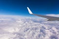 View of the wing of an airplane flying above the clouds at high altitude under a blue sky from the passenger window. In flight Royalty Free Stock Photo