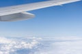 View of wing from window of airplane flying high altitude with clouds and clear blue sky background Royalty Free Stock Photo