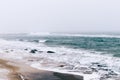 View of a winter beach and the sea during a snowfall and wind, o