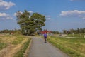 View of woman on bicycle on bicycle paved road on summer day.