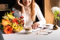 View of woman with bouquet of autumn flowers in cafe with smartphone and notebook Royalty Free Stock Photo