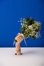 View of woman with bracelet holding bouquet of small spring flowers isolated on blue