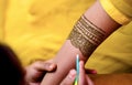 View of a woman drawing traditional Henna Mehandi body art on a hand