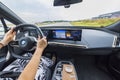 View of woman driving new electric car BMW IX 40.