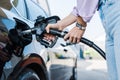 View of woman holding fuel pump while refueling car with benzine
